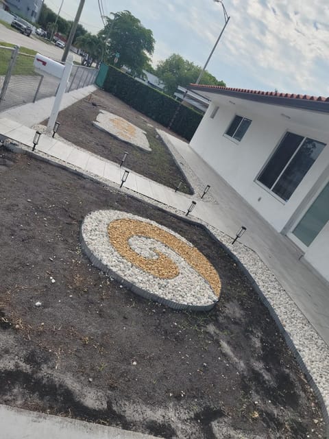 Front yard mid-install: a white and gold pebble spiral set into freshly graded soil