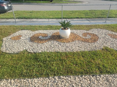 Finished verge: a scrolled white and gold pebble mosaic with a sago palm urn in fresh sod