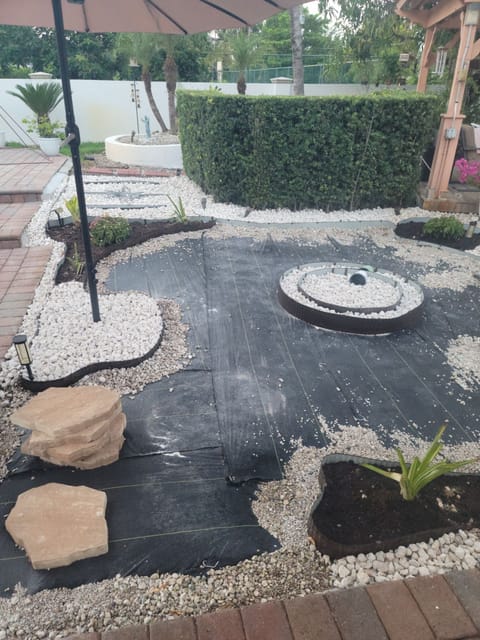 Back yard mid-build: landscape fabric pinned down, stone rings set out and flagstone ready to lay