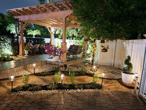 Back yard after dark: cedar pergola, paver terrace and planted beds lit by path lights